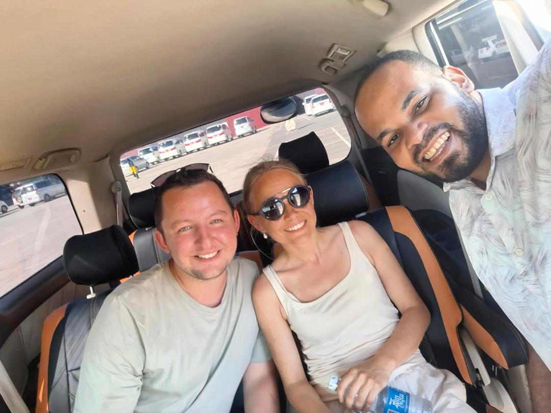 Happy tourists with their Kai Tours and Safaris driver inside an Alphard transfer at Zanzibar airport