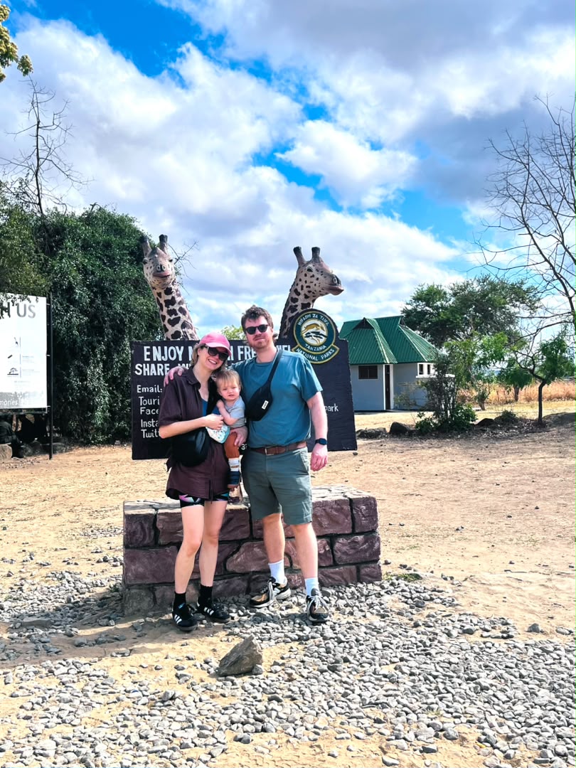 Parents holding their baby at the welcome sign on a Mikumi family safari